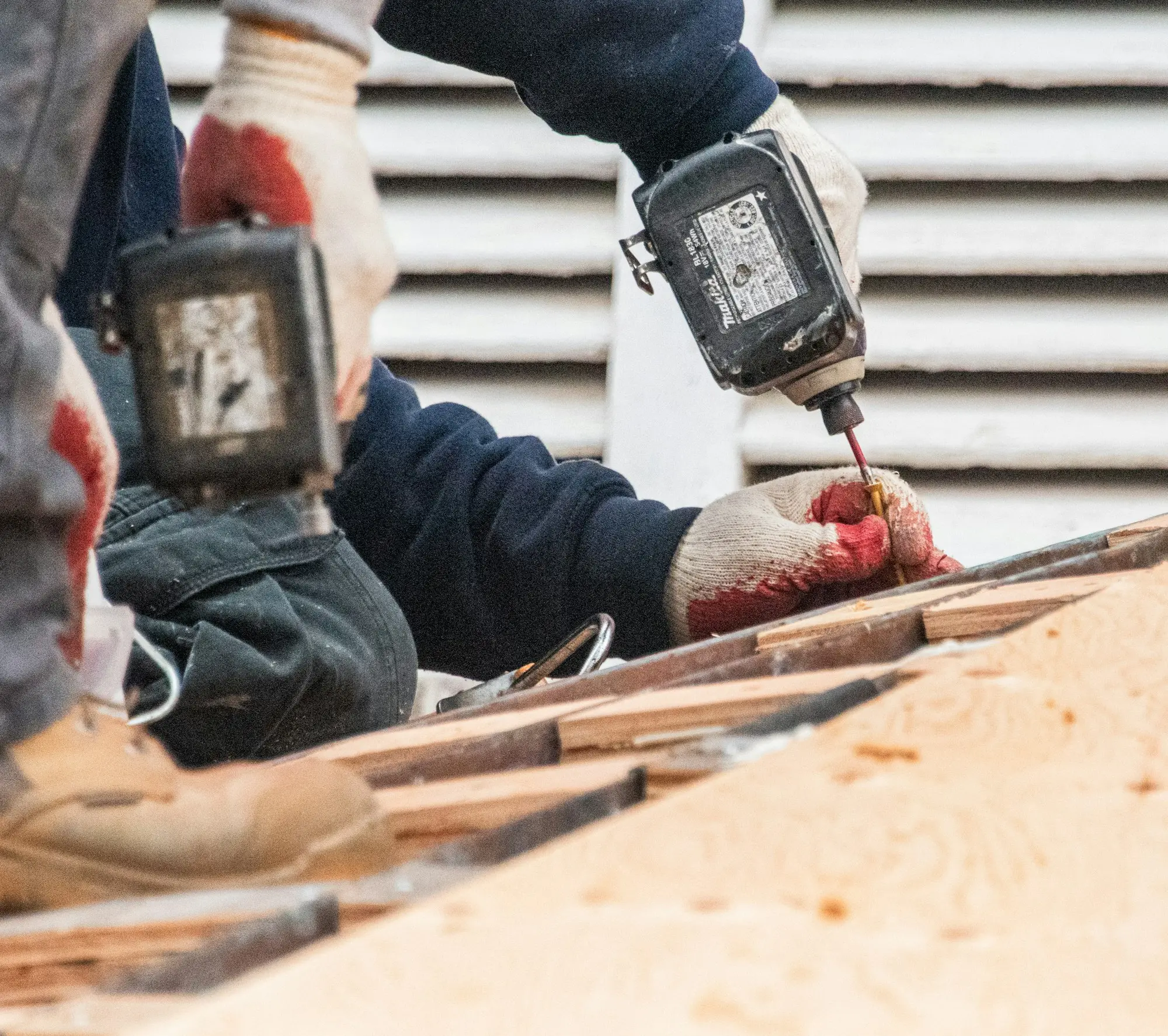 Tradesperson using a power drill on timber during repair work