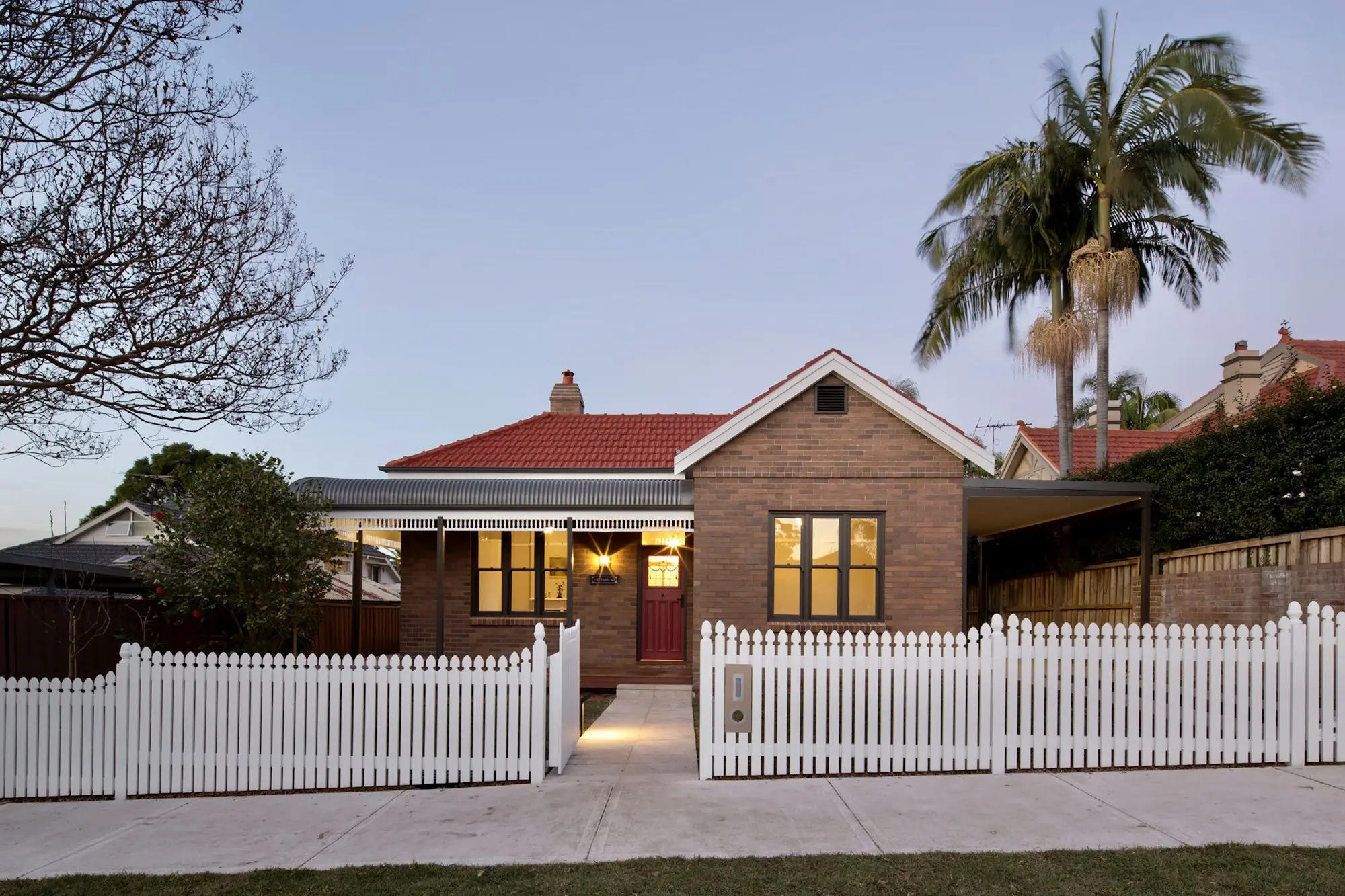 Red-brick home with a white picket fence on a suburban street in Chatswood, NSW